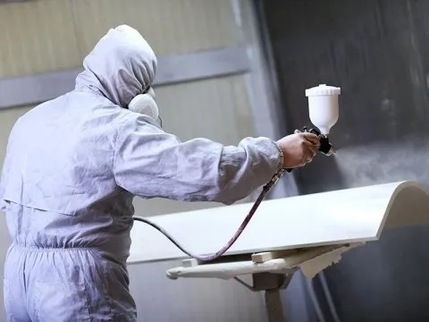 Operatore in tuta protettiva durante verniciatura industriale